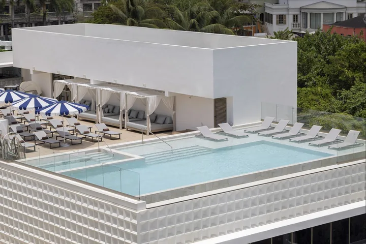 Rooftop pool with loungers, umbrellas and views toward the sea at Royalton Vessence Barbados.