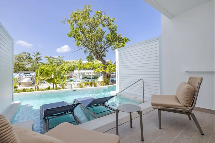 Private terrace chairs beside submerged loungers and direct swim-out pool access at Royalton Vessence Barbados.